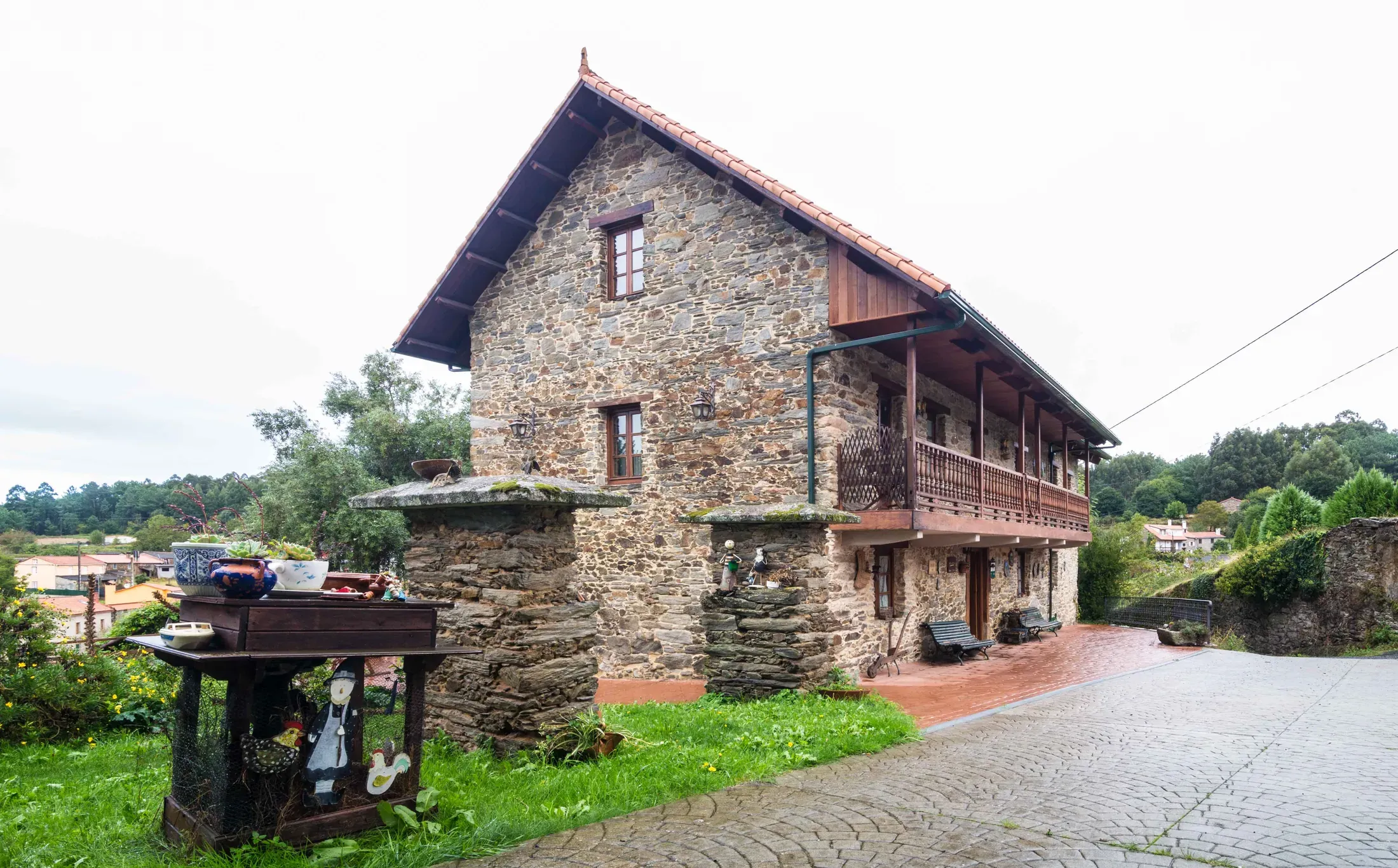 Fachada lateral de la casa con galería de madera y marquesina para el coche