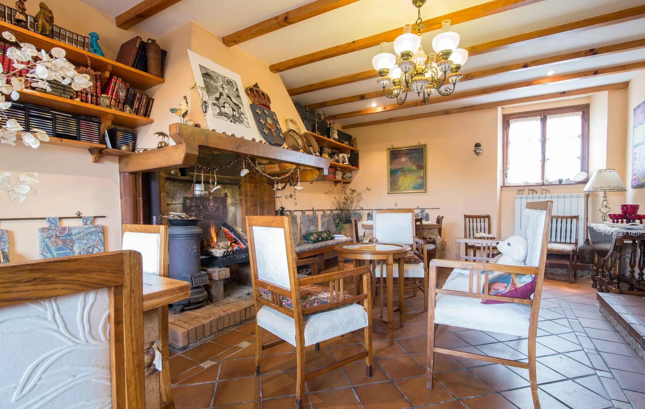 Salón con chimenea de piedra, sofás y estanterías con libros
