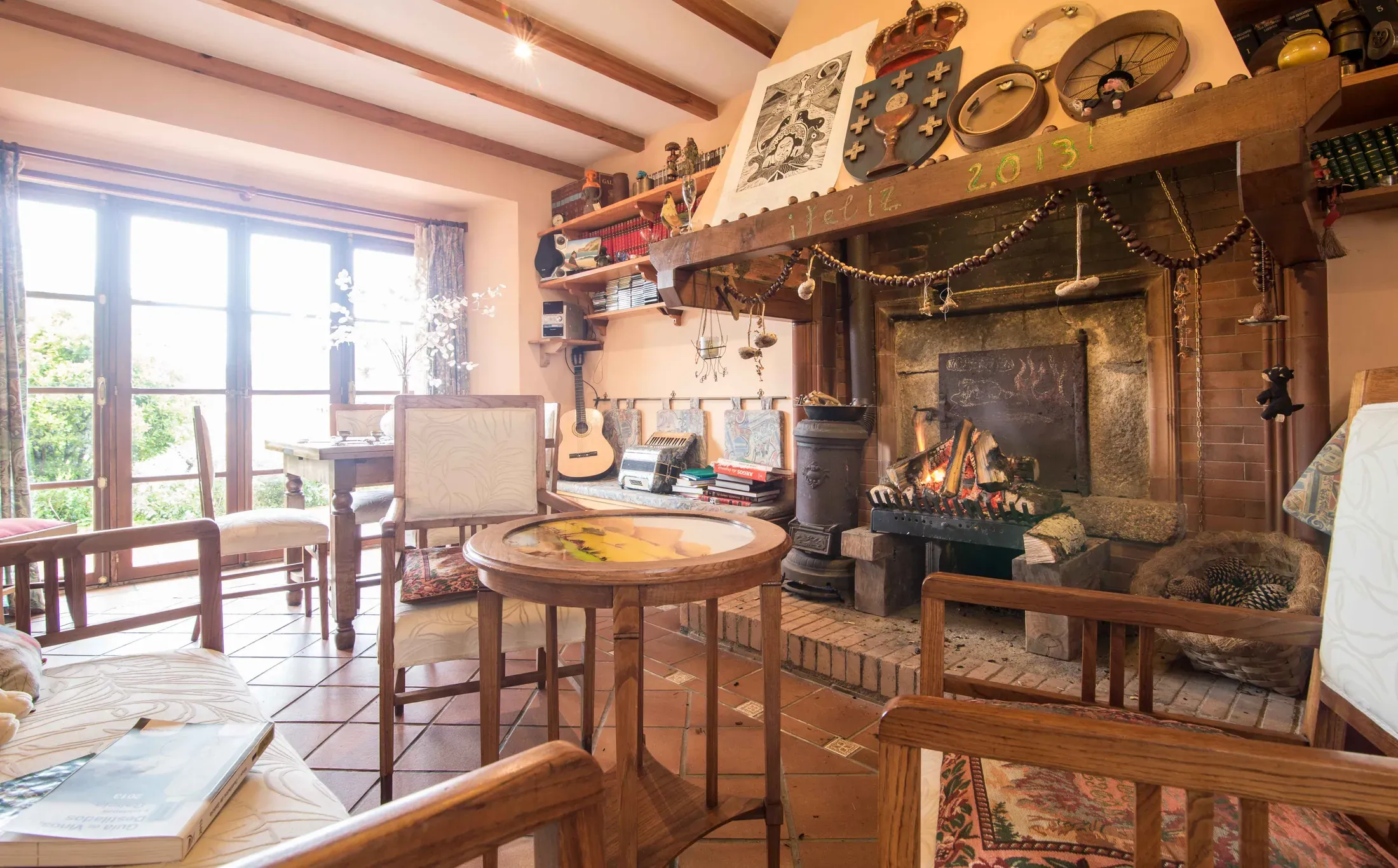 Salón con chimenea encendida, ventana grande y guitars colgadas en la pared