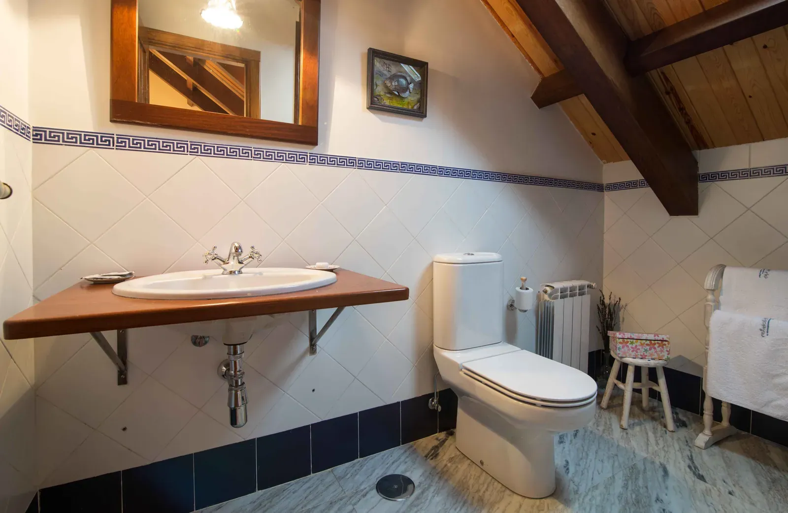 Baño con lavabo de madera, inodoro y bidé, iluminado por una claraboya