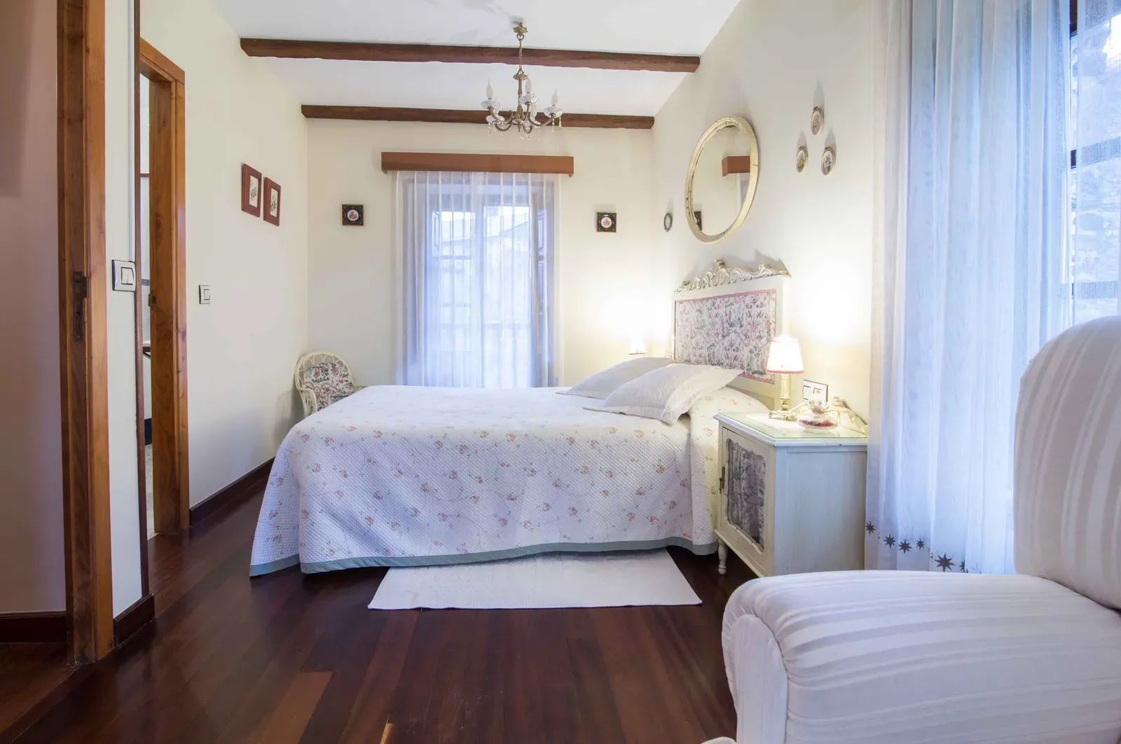 Habitación doble con colcha blanca, armario y lámpara de araña