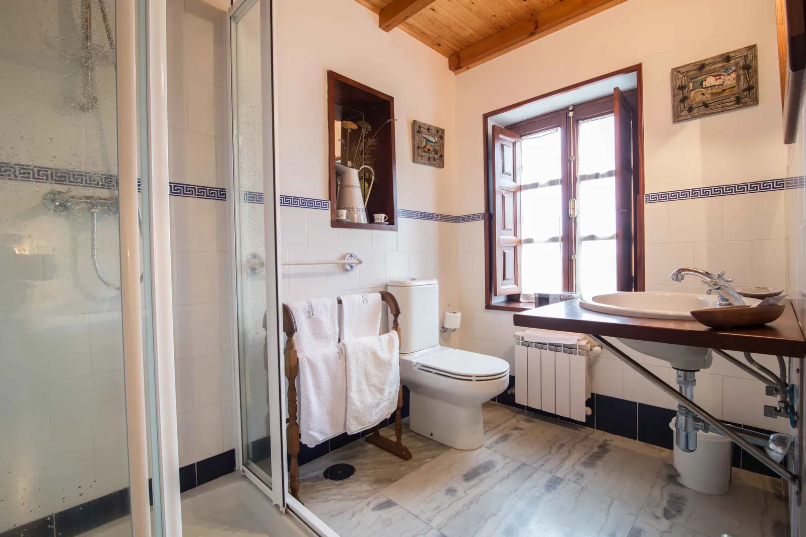 Baño con ducha, lavabo de madera y ventana